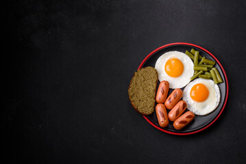 Tasty English breakfast of fried eggs, beans, asparagus, sausages with spices and herbs