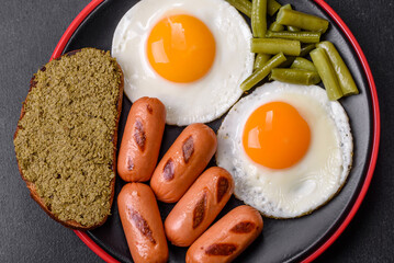 Tasty English breakfast of fried eggs, beans, asparagus, sausages with spices and herbs