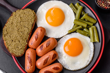 Tasty English breakfast of fried eggs, beans, asparagus, sausages with spices and herbs