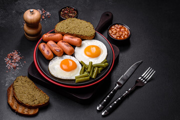Tasty English breakfast of fried eggs, beans, asparagus, sausages with spices and herbs