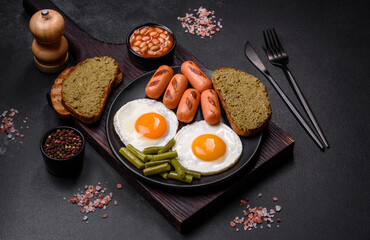 Tasty English breakfast of fried eggs, beans, asparagus, sausages with spices and herbs