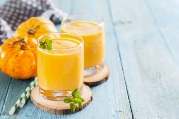 Pumpkin smoothies in a glass on blue background. Autumn Warming Spice Drink. Copy space