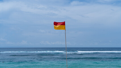 beach safety flag over a blue sky and ocean background 