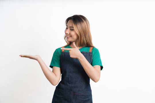 Young Asian Woman Dressed In Barista Uniform Pointing Finger To The Side On White Background.