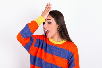 Young caucasian woman wearing colorful knitted sweater over white background surprised with hand on...