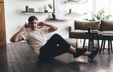 Man doing sport exercise at home sitting on floor pumping abs