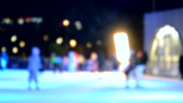 Many people skating on openair ice skating rink on winter night. Multicolored light music coloring illumination colorful backlight lighting shining Activities entertainment Blurred abstract background