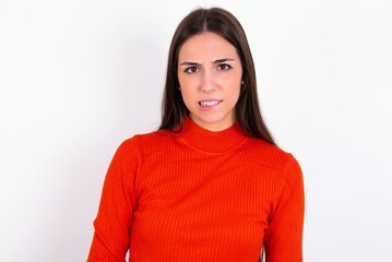 Portrait of dissatisfied Young caucasian woman wearing red sweater over white background smirks...