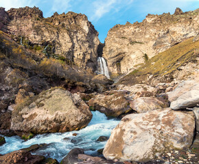 Scenic autumn landscape with vertical big Sultan waterfall at mountain top in sunshine in the Jila-Su tract. Kabardino-Balkaria. Russia, Caucasus. High falling water in Northern Elbrus region.