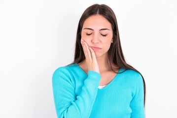 Young caucasian woman wearing blue sweater over white background with toothache