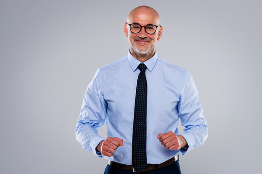 Smiling mature male CEO with arms crossed standing at isolated background