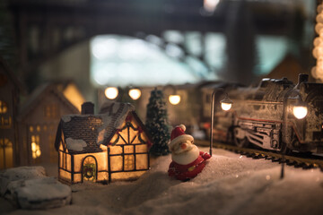 Miniature of winter scene with Christmas houses, train station, trees, covered in snow. Nights scene. New year or Christmas concept.