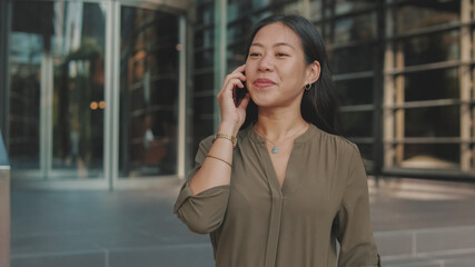 Young businesswoman talking on smartphone on business center background