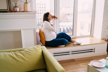 Pregnant woman with big belly eating croissant