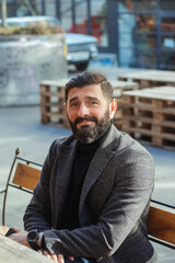 brutal bearded middle-aged man in a street cafe