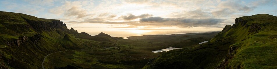 Obraz premium Panoramic shot of Quiraing on Isle of Skye in Scotland under cloudy blue sky at sunrise.