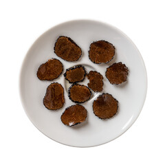 Truffle carpaccio slices on a white plate cutout. Sliced black truffle in oil isolated on a white background. Canned Tuber melanosporum. Gourmet ingredient taste of delicacy mushroom.