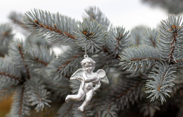 angel figurine fir pine cone spruce tree toy hanged outside from natural from garden park or forest.stop cutting trees concept decorations outside outdoor.silver angel toy against cloudy winter sky