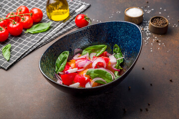 Vegetable salad with tomatoes and cucumbers on dark brown table