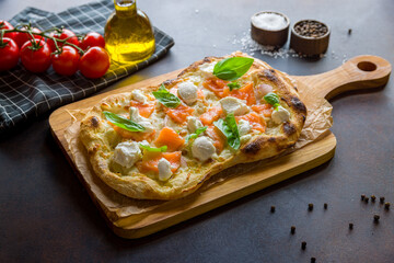 Pizza with salmon and cheese on Roman dough on dark brown table