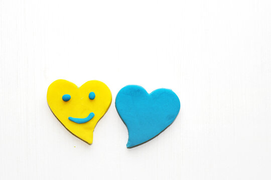 clay plasticine hearts kid child hand diy do it yourself activities happy valentines day february 14th.blue yellow colour heart isolated.smile sad emotion emoji creative little preschooler boy