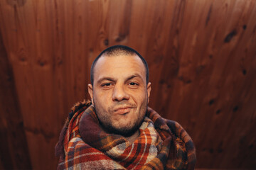 a man in a plaid on a wooden background with a satisfied expression