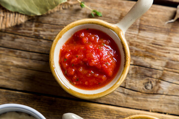 tomato sauce in a saucepan on wooden table top view