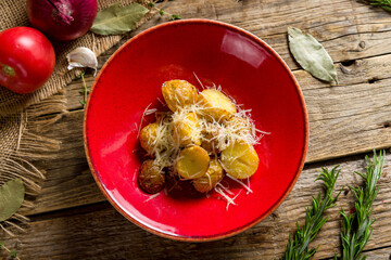 baked mini potatoes with parmesan on red plate on wooden table top view