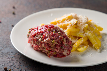 Tartare from beef with french fries on dark stone table macro close up