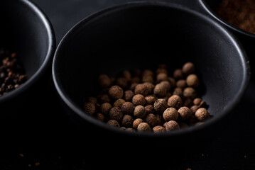 Allspice in black bowl. Dark backgrpund. 