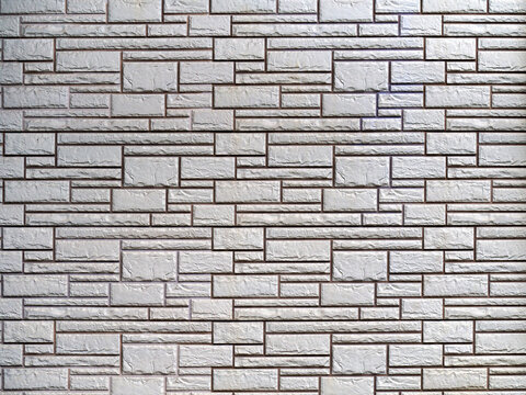 Fototapeta The gray brick wall consists of rough decorative bricks of various sizes and shapes. Abstract geometric stone background.