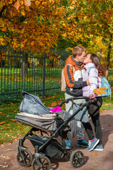 Parents mom and dad walking with a stroller in the autumn park