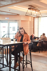 Fototapeta na wymiar beautiful young woman with a cup of takeaway coffee and donuts sits in a cafe