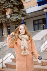 beautiful young woman with takeaway coffee outdoors in cold weather