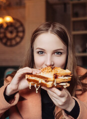 beautiful young woman in a cafe eating a sandwich