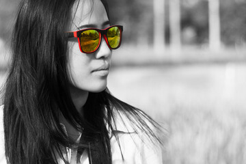 Close up image of asian woman in sunglasses posing sideways outdoors in black and white