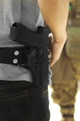 Man carrying pistol weapon in holster at hip belt.