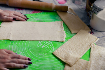 A woman prepares dough for cooking. Sliced dough pieces ready for baking