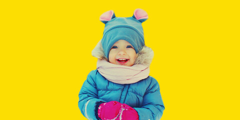 Winter portrait of cute happy little child on yellow background