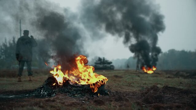 A Ukrainian tank T-72 drives through the trenches on battlefield, through burning tires. Training on a shooting range. Armed Forces of Ukraine.