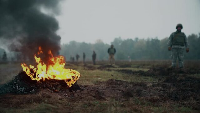 Ukrainian soldiers stand at training and wait for the command.. Burning tires in the foreground. Armed Forces of Ukraine.