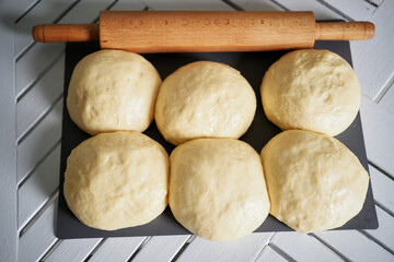 Rolling pin and balls of dough on a wooden board, soft selective focus. Small balls of dough with flour for pizza or cakes and scones. Shallow depth of field. High quality photo