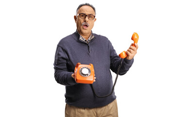 Angry mature man holding a vintage rotary phone and looking at camera