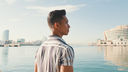 Young man is standing on the pier. Back view