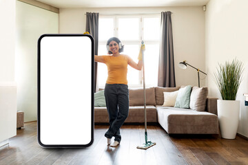 Young Arab Woman Cleaning Home And Standing Near Big Blank Smartphone