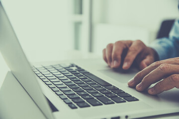 Closeup man hands typing on computer keyboard. Businessman using laptop at home. Office workplace