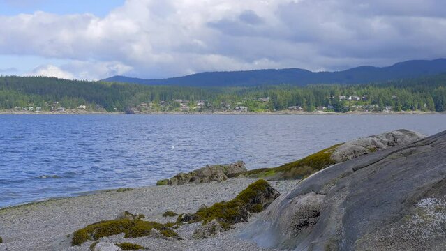 202 Establishing aerial shot of ocean beach with rocks and pebbles in slow motion at summer day in Vancouver, Canada, North America. Day time on September 2022. Drone forward. ProRes 422 HQ.