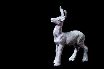 Christmas tree toy, shining silver deer standing on a black background, close-up. little Santa helper decoration
