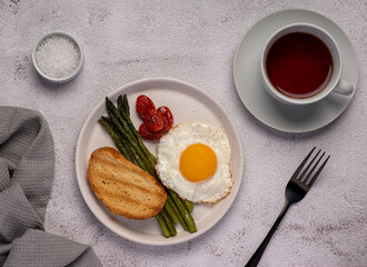 Food photography of fried egg, tomato, asparagus, toast, tea, salt, breakfast