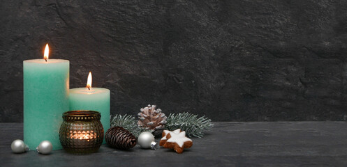 Festliche Weihnachtsdekoration mit Kerzen und Weihnachtskugeln vor einer Schiefer Wand mit Platz...